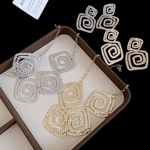 Detailed view of textured square spiral necklace and earring jewelry sets in gold and silver