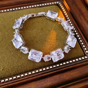 Macro shot of silver-toned bracelet with square zircon inlays on green velvet