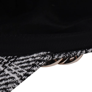 Detail of classic houndstooth pattern and golden chain on a vintage baker boy cap