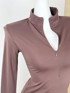 Detail of a brown slim-fit sports shirt showing the zipper neckline and knit texture