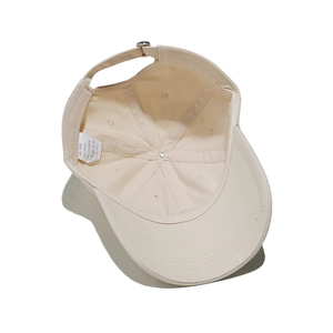 Detailed interior of a beige cotton baseball cap featuring reinforced seams and metal buckle