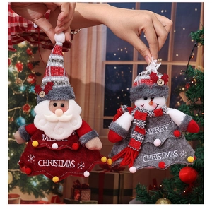 Hand holding fabric Christmas gift bags featuring Santa and snowman motifs with knitted details