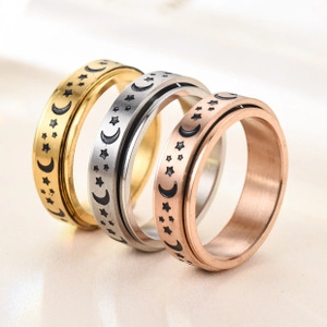 Close-up of three rotatable rings with star and moon patterns in gold, silver, and rose gold