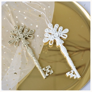 Detail of gold glitter and white embossed resin key ornaments on a metallic tray