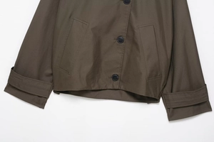 Detailed close-up of dark olive trench coat featuring buttons and textured fabric