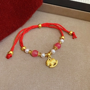 Dettaglio del bracciale in corda rossa intrecciata con ciondolo a cavallo e perle