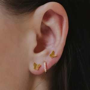 Close-up of gold butterfly stud earring and micro-set zircon hoop on the ear