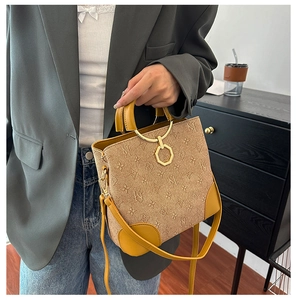 Close-up of khaki canvas bucket bag with yellow leather trim and golden metal ring handle