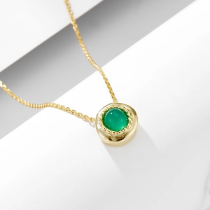 Detail of s925 silver green agate pendant with gold chain on white geometric background