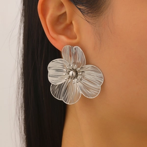 Close-up of silver wire-wrapped flower earring with a polished bead center on a model
