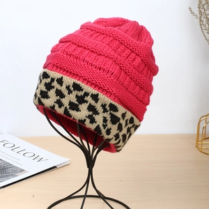 Pink knit beanie with leopard print cuff shown on a display stand for winter warmth