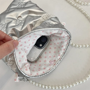 Dettaglio borsa argento con trama a fiocco, catena di perle e fodera a pois