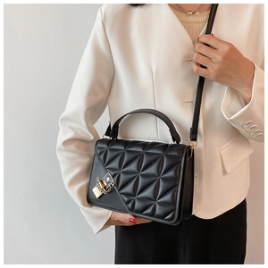 Détail du sac bandoulière matelassé noir avec boucle dorée et chaîne sur modèle