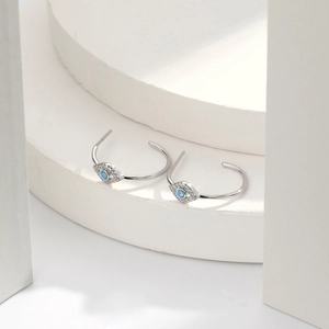 Detail of silver S925 devil's eye hoop earrings with blue opal and white zircons