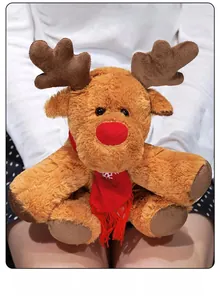 Close-up of soft plush reindeer toy with red snowflake scarf being held by a person
