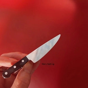 Miniature chef knife hair clip with silver blade and black handle on red background