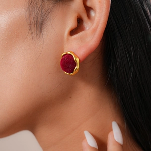 Close-up of vintage gold round stud earrings with red velvet inlay worn by a model