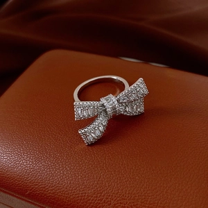 Detailed close-up of a silver bow ring with zircon pavé on luxury leather box