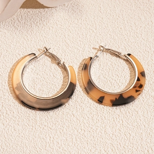 Gros plan détaillé de grandes boucles d'oreilles en résine en C avec textures gris fumé et ambre