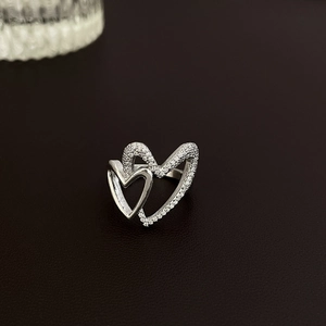 Close-up of interlocking silver double heart ring featuring paved white zircons and polished finish