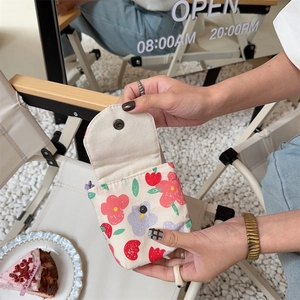 Detail of floral canvas mini pouch with metal snap button in a lifestyle cafe setting