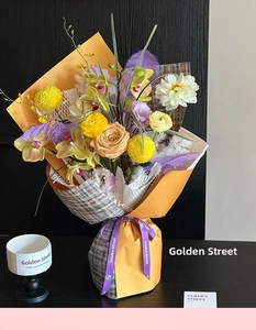 Detail of premium floral bouquet wrapped in orange waterproof and brown plaid papers