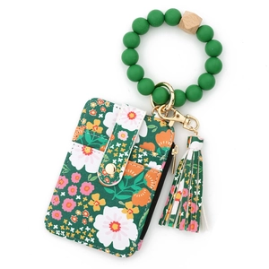 Détail du porte-cartes à fleurs vertes avec bouton pression doré et bracelet en perles