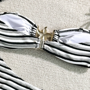 Detail of black and white striped bikini top featuring a golden starfish buckle