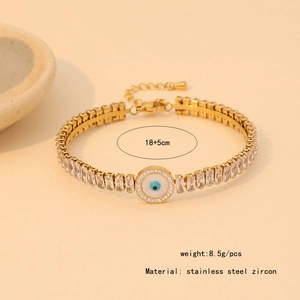 Dettaglio del bracciale in acciaio inossidabile dorato con zirconi e ciondolo malocchio