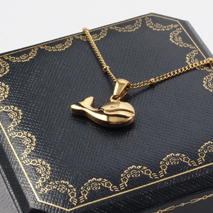 Polished gold whale pendant necklace on navy jewelry box with a delicate gold chain