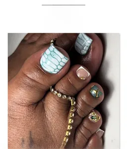 Macro shot of green snake skin pattern and crystal studded press-on toe nails JP4254