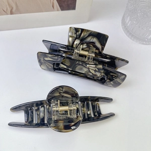 Detail of large acetate hair claws with marble pattern and strong gold metal springs