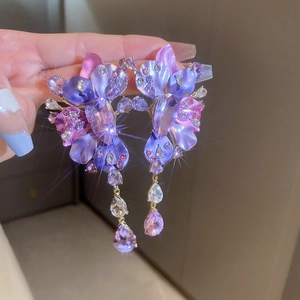 Detailed view of floral purple crystal drop earrings with sparkling tassels and star flare