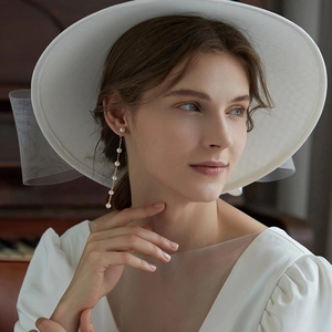 Elegant silver needle pearl tassel earrings on model with white wide-brimmed hat
