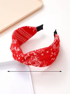Detail of red paisley print knotted headband featuring soft fabric and protective ends