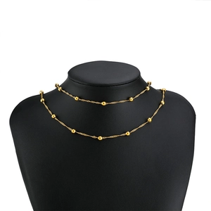 Detail view of a double-layered gold stainless steel water wave chain with beads on a black bust