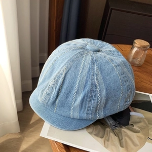 Close-up of light blue denim newsboy hat with vertical white stitching and retro texture
