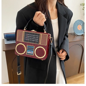 Detailed close-up of retro radio acrylic clutch bag with wine red finish and gold hardware