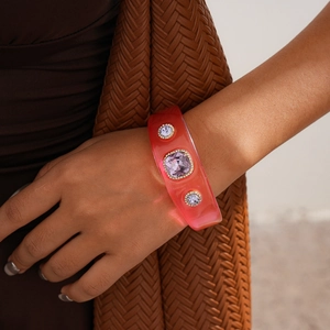 Close-up of pink translucent resin bangle with sparkling purple crystals on brown fabric