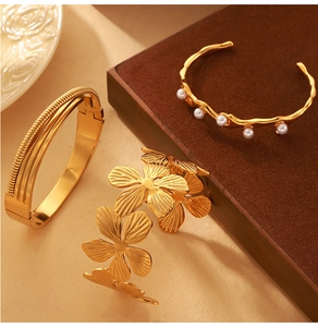 Detail of 18K gold textured floral cuff and wave pearl bracelet set on display
