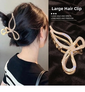 Detail view of a large bow hair claw clip with golden finish and pearlescent acetate inlay