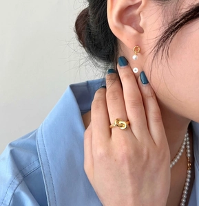 Detail of 925 sterling silver knot ring paired with elegant pearl jewelry on a model
