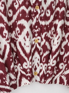 Detail of red ikat print shirt with cotton linen texture and yellow wood-style buttons
