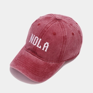 Detail of washed red baseball cap featuring white NOLA embroidery and stitched brim