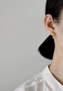 Detailed close-up of a gold S925 silver hoop earring with textured woven pattern on ear