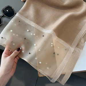 Detail of champagne silk scarf with sheer mesh edge and elegant pearl bead embellishments