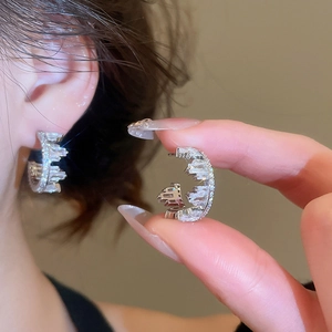 Detailed close-up of silver C-shaped zircon earrings with high-shine cubic zirconia inlay