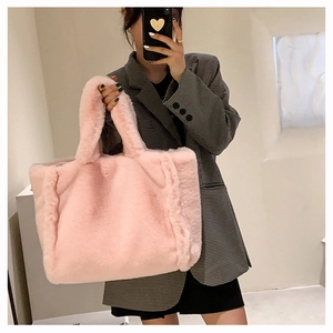Détail d'un sac cabas rose en peluche à texture douce tenu par un mannequin en intérieur