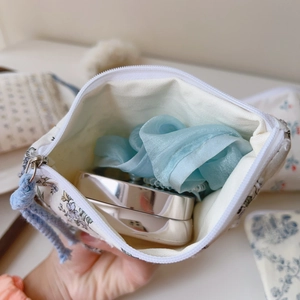 Detailansicht der kleinen geblümten Tasche mit Spiegel und Haargummi im Inneren