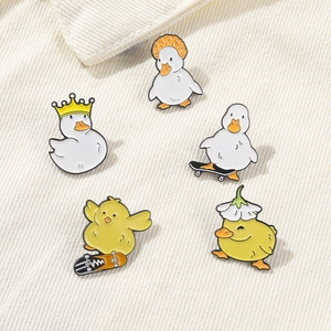 Set of 5 cartoon yellow duck enamel pins with crown and skateboard on white fabric